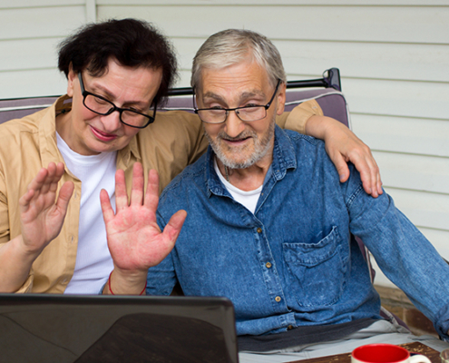 Happy older couple waving to laptop screen